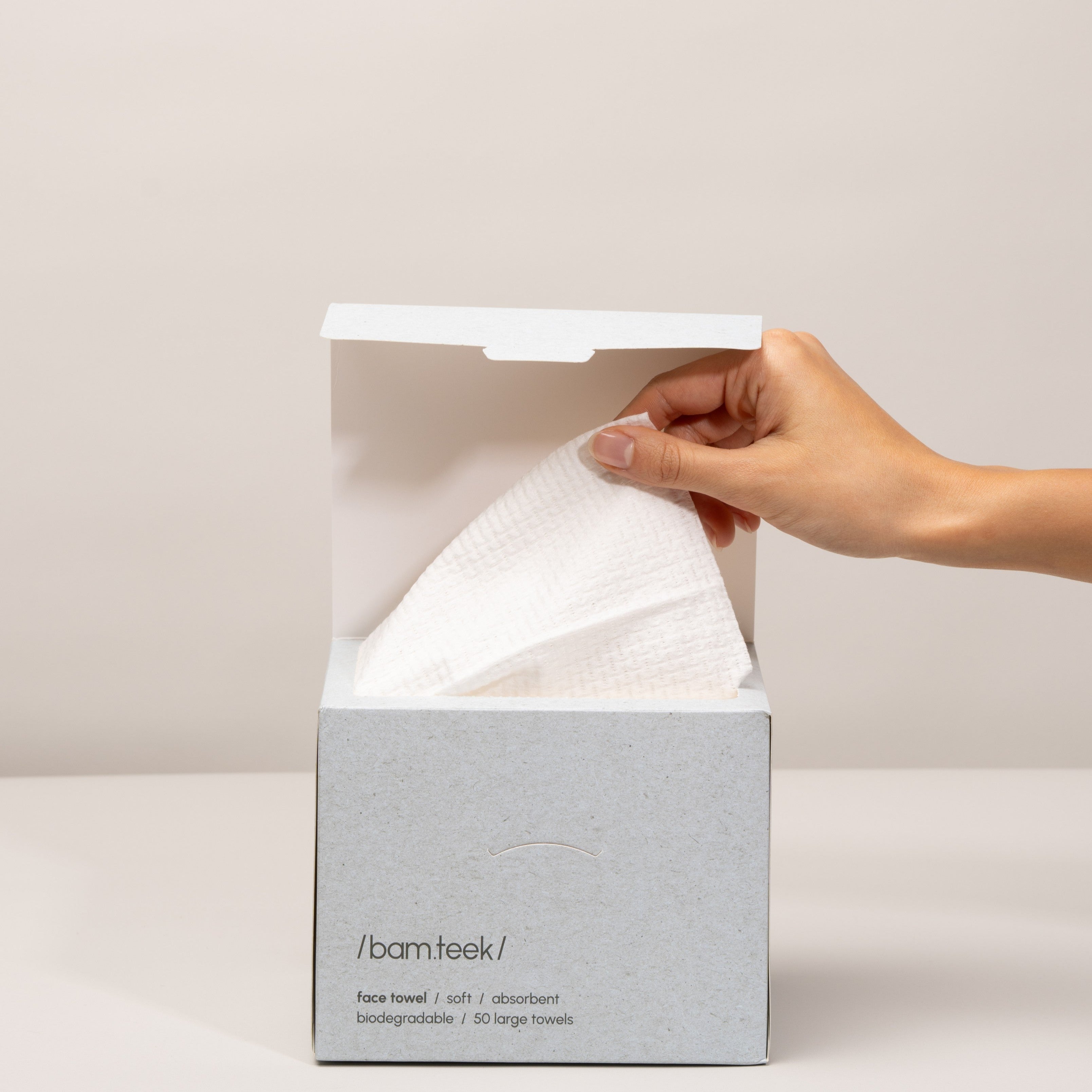 Hand pulling a soft, absorbent Face Pack towel from a sleek box by Bamteek.