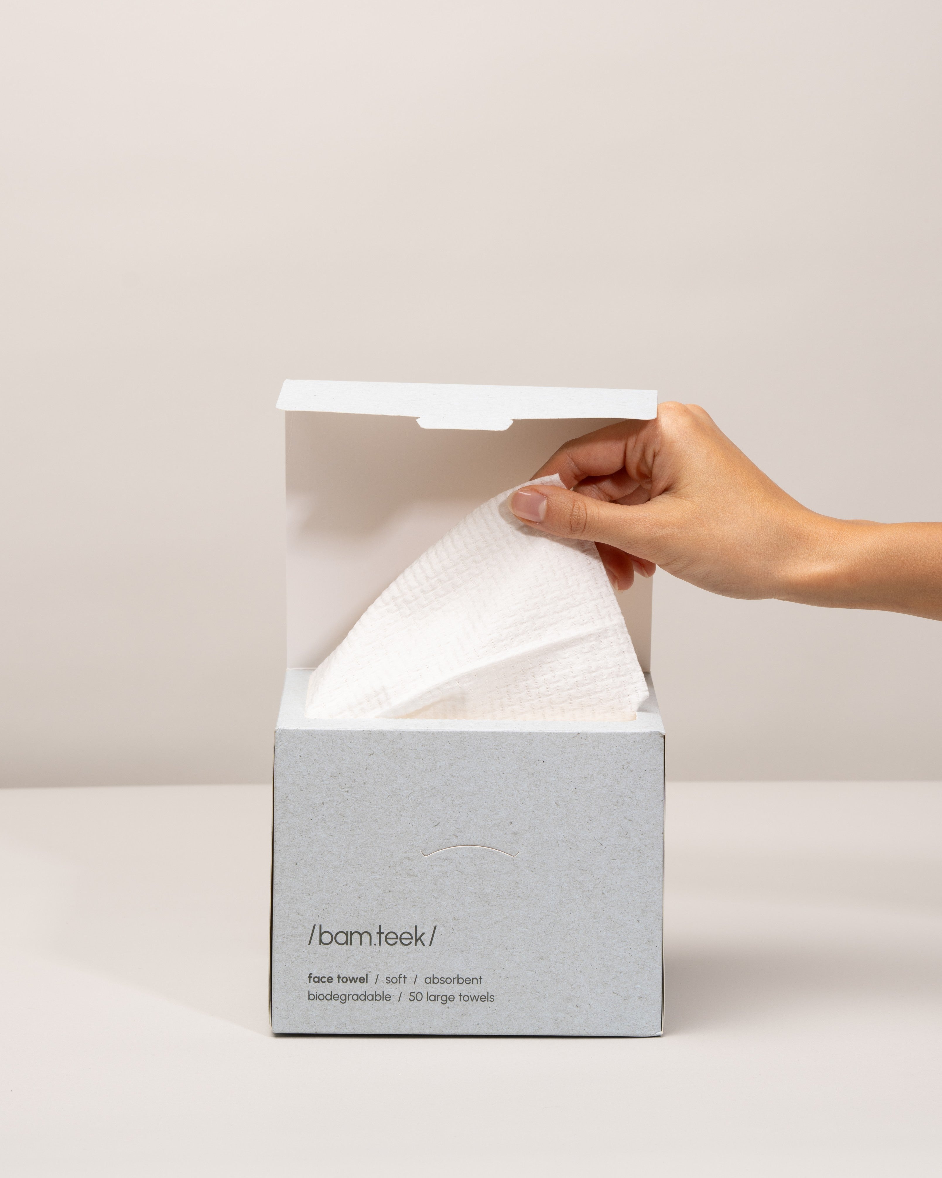 Face Bundle by Bamteek showing a hand pulling a single-use towel from the box for hygienic skincare.