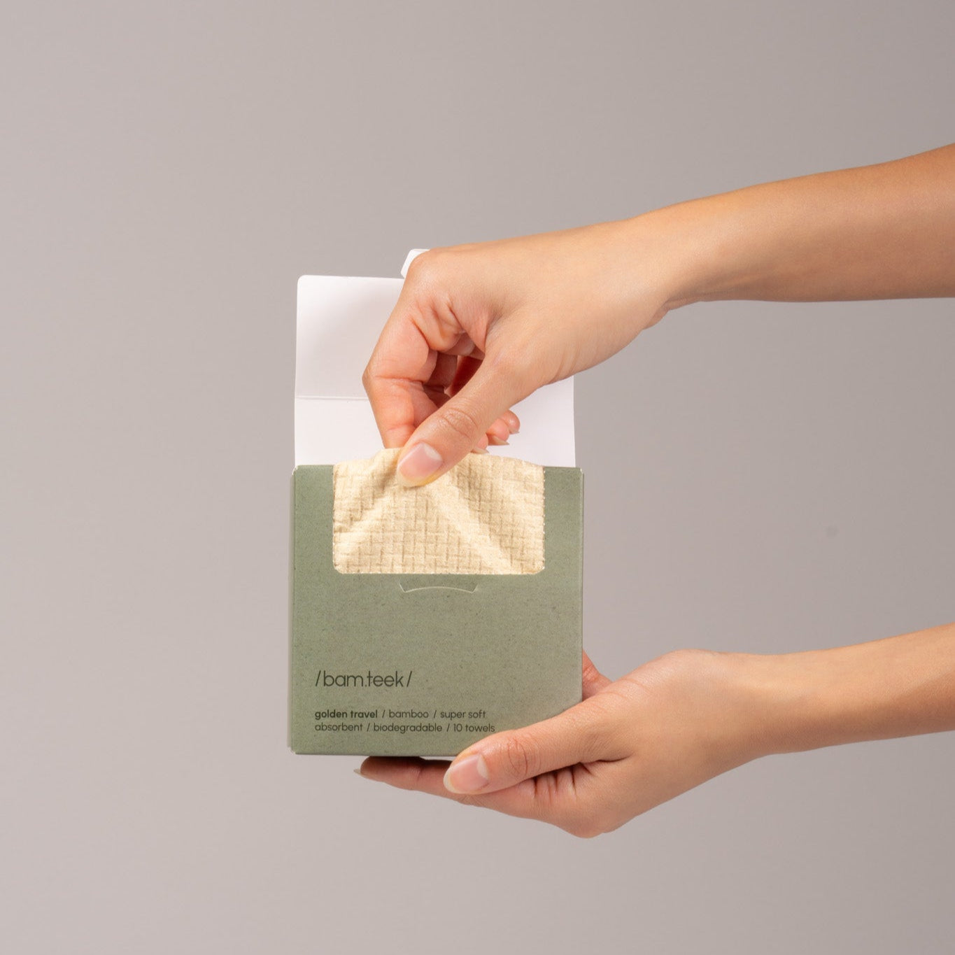 A Kuwaiti Hand holding Golden Travel Bundle with bamboo towel, showcasing sensitive skincare solution.