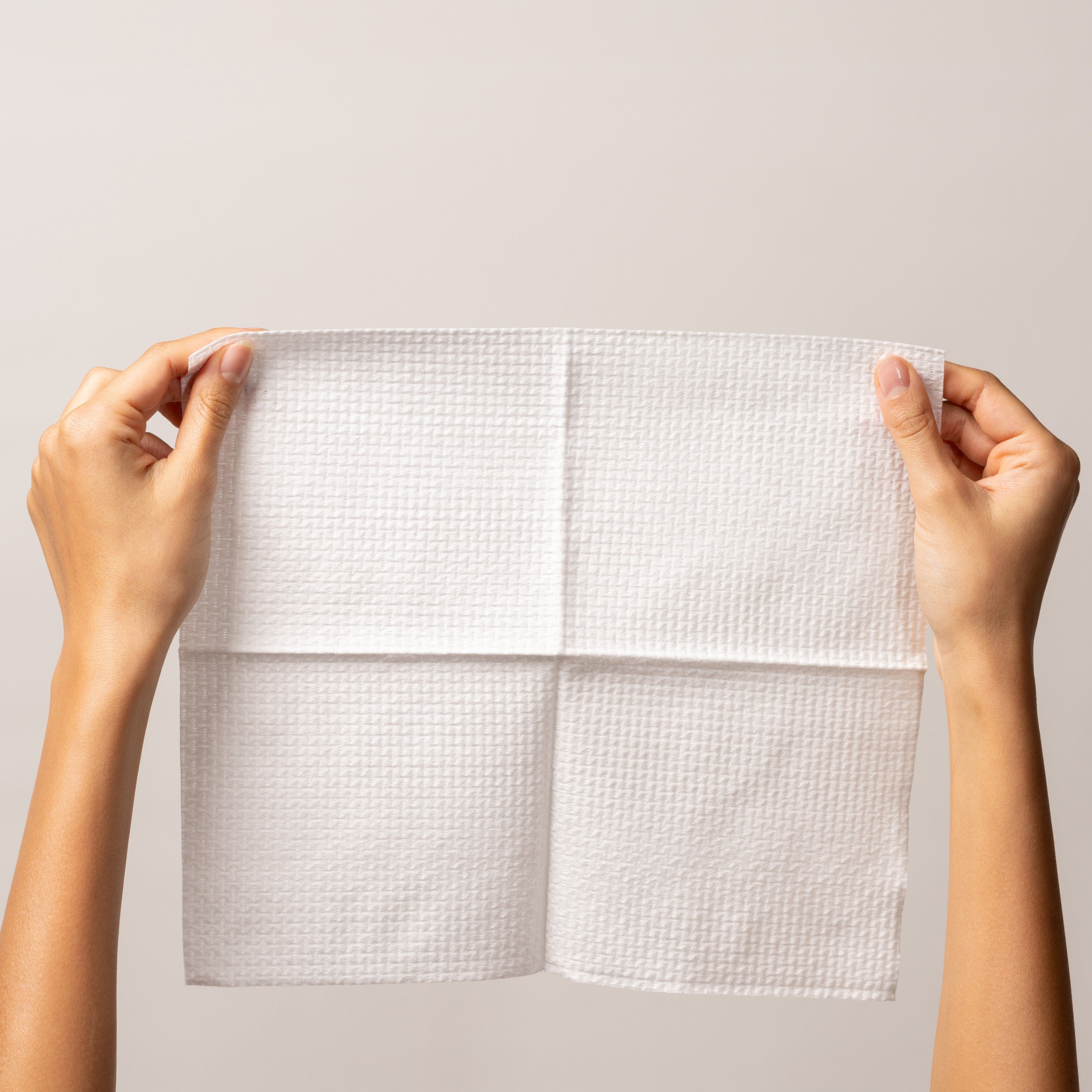 Hands holding a soft, absorbent single-use Face Pack towel for clean skincare on the go.