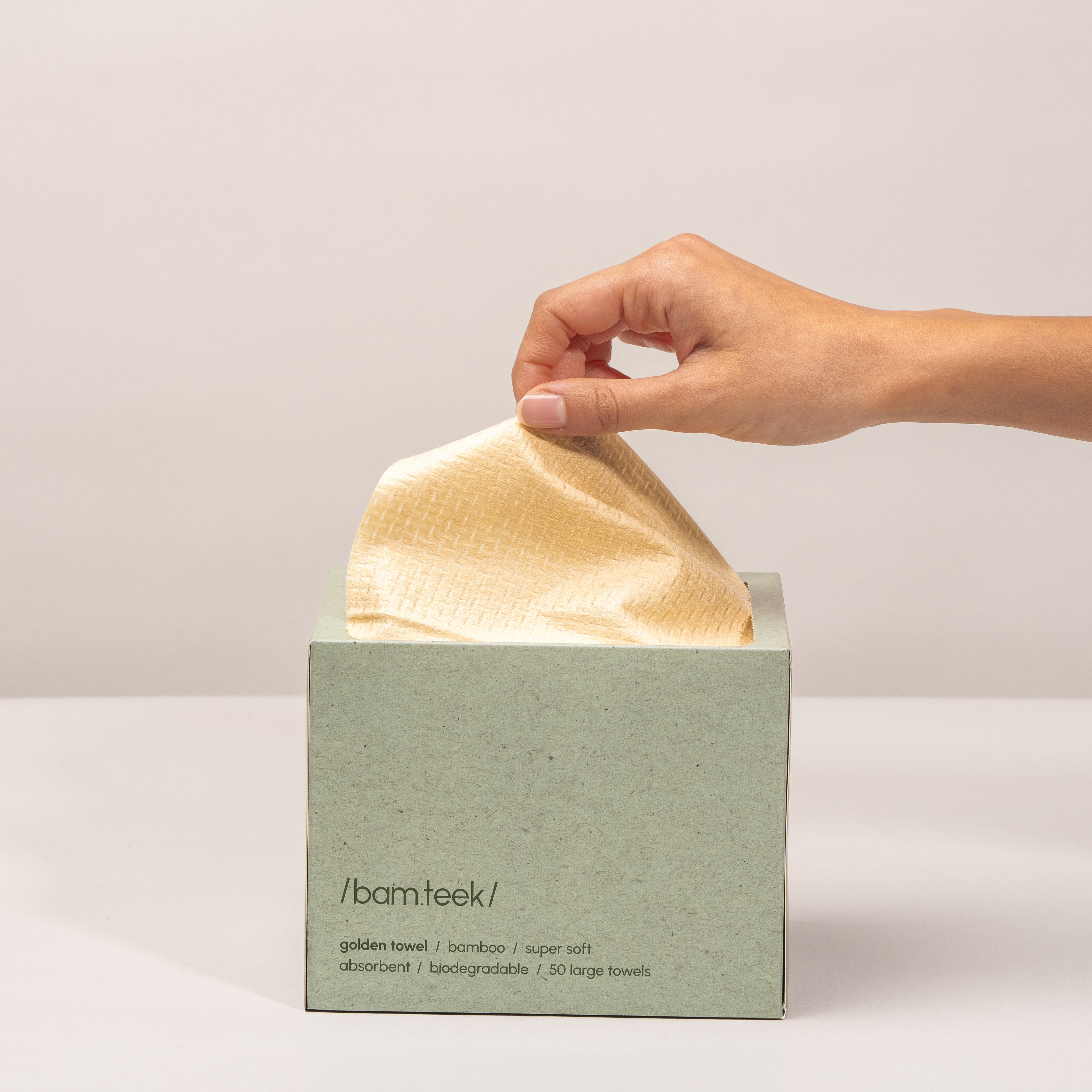 A Kuwaiti hand pulling a golden towel from the eco-friendly Golden Pack by Bamteek for sensitive skincare.