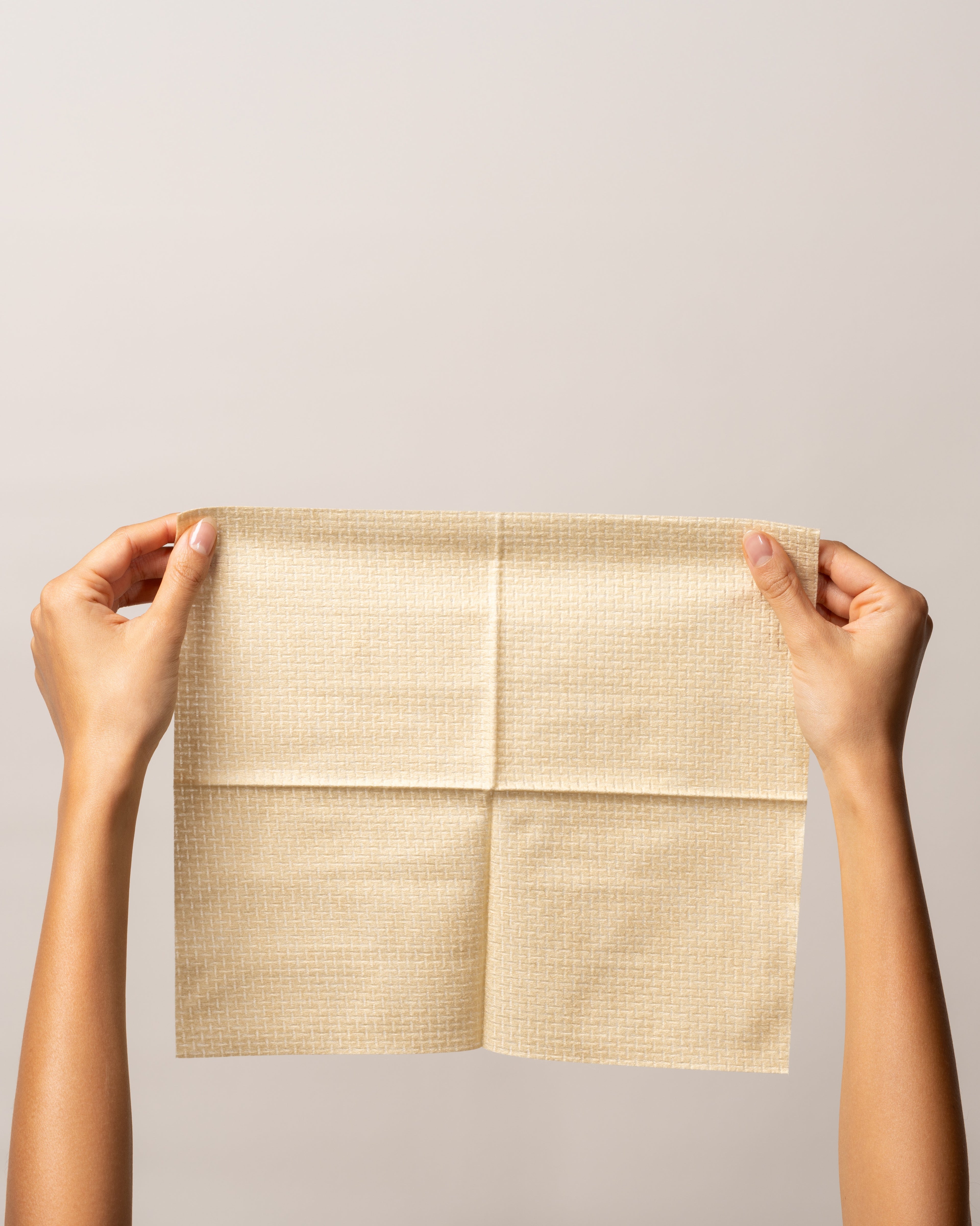 Golden Bundle - single-use bamboo towel held up, showcasing its soft texture and eco-friendly material.